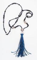 sautoir från svart pärlor med blå borsta på vit foto