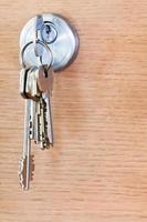 knippa av hus nycklar i låsa av trä dörr foto