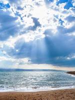 solljus passerar genom blå moln över död- hav foto