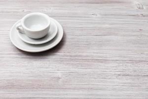 ett vit kopp med tefat på grå brun tabell foto