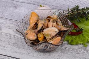 inlagda musslor i skålen serveras peppar, vitlök och sallad foto