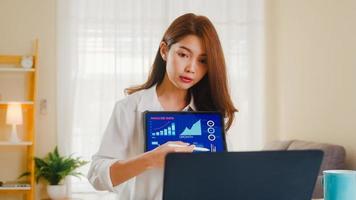 asiatisk affärskvinna som använder bärbar dator och surfplatta hemma foto