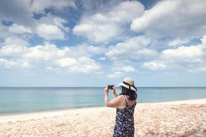 kvinna tar fotografi på stranden foto