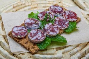 salami smörgås på trä- styrelse och trä- bakgrund foto