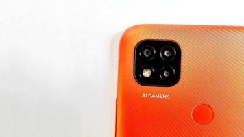 orange smartphone med kameror med artificiell intelligens under vit grå bakgrund. lämplig för företags- och industrireklam, affisch, bakgrund, marknadsföring, teknikföretag, etc. foto