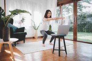 kvinna som lär sig online-träningskurser hemma från bärbar dator foto