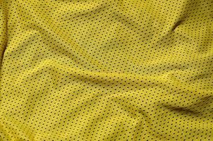 sport Kläder tyg textur bakgrund, topp se av gul trasa textil- yta foto