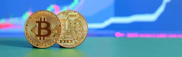 två guld bitcoins lögn på de grön yta på de bakgrund av de visa, som skildrar de tillväxt av de placera på de Diagram foto