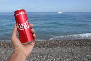 antalya, Kalkon - Maj 18, 2021 original- coca cola röd tenn kan lögner på små runda sten stenar stänga till hav Strand. Coca Cola kan i manlig hand på strand foto