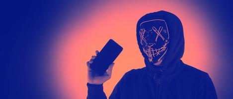 digital säkerhet begrepp. anonym hacker med mask innehav smartphone hackad. foto