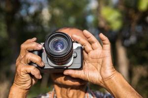 närbild se av både händer av ett äldre thai man innehav en filma kamera. foto