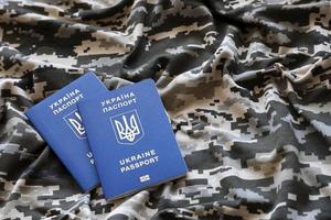 sumy, ukraina - Mars 20, 2022 ukrainska utländsk pass på tyg med textur av militär pixeled kamouflage. trasa med camo mönster i grå, brun och grön pixel former och ukrainska id foto