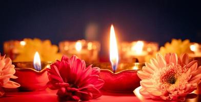 Lycklig diwali. traditionell indisk festival av ljus. brinnande diya olja lampor och blommor på röd bakgrund. foto