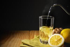 glas av varm infusion ingefära citron- dryck. organisk och friska livsstil. färsk vatten med citron- skivad. närvarande på tabell med naturlig ljus förbi de fönster. säsong- dryck. foto