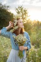 vacker flicka går på fältet på sommaren med vilda blommor. foto