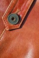 brun läder textur. användbar som bakgrund för några design arbete. makro Foto av en knapp på yttre Kläder tillverkad av äkta läder