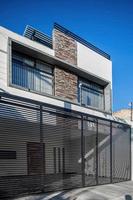 Fasad av en modern hus med sten, häfta den där wraps de fönster målad i grå, metall ingång, järnsmide foto