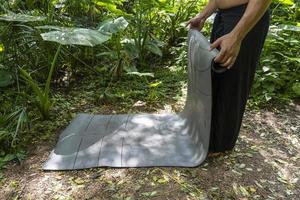 ung brun latin man, rullande upp hans matta till övning i de skog, omgiven förbi vegetation, mexico latin Amerika foto