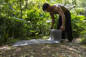 ung latin man arrangera hans yoga matta, inuti en skog på en enkel, direkt Kontakt med natur, mexico foto