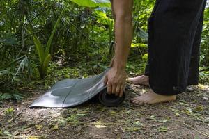 ung brun latin man, rullande upp hans matta till övning i de skog, omgiven förbi vegetation, mexico latin Amerika foto