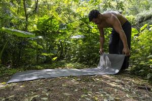 ung latin man arrangera hans yoga matta, inuti en skog på en enkel, direkt Kontakt med natur, mexico foto