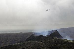 helikopter svävande över en rökning vulkan i island foto