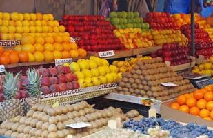 en frukt säljare bås i armenia fylld med färgrik frukt. tecken visa de namn av de respektive frukt - armeniska för apelsiner, kiwi, äpplen, kvitt foto