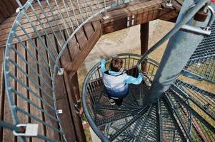 pojke promenad på spiral trappa på trä- observation torn. foto