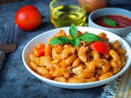 makaroner pasta med tomat sås i vit tallrik på grå Färg tabell foto