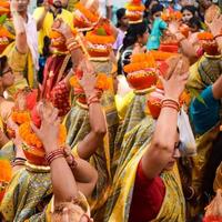 New Delhi, Indien 3 april 2022 - kvinnor med kalash på huvudet under jagannath-templet mangal kalash yatra, indiska hinduistiska hängivna bär jordkrukor som innehåller heligt vatten med en kokosnöt på toppen foto