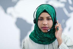 afrikansk muslim kvinna med telefon headsetet portion och stödjande uppkopplad foto