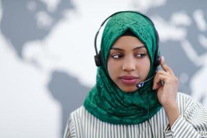 afrikansk muslim kvinna med telefon headsetet portion och stödjande uppkopplad foto