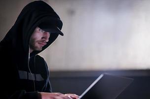 begåvad hacker använder sig av bärbar dator dator medan arbetssätt i mörk kontor foto