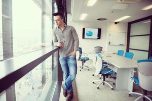 ung företag man använder sig av smart telefon på kontor foto