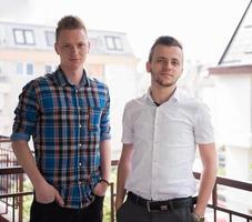 två ung män stående på balkong foto