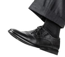 manlig vänster fot i svart sko tar en steg foto