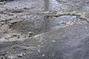 skadad asfalt väg med gropar orsakade förbi frysning och upptining cykler under de vinter. fattig väg foto