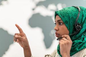 afro muslim kvinna med grön hijab scarf kund representativ företag kvinna med telefon headsetet portion och stödjande uppkopplad med kund i modern ring upp Centrum foto