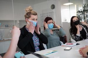 verklig företag människor på möte bär skyddande mask foto