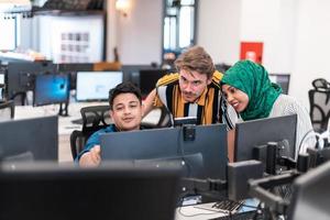 multietnisk börja företag team kvinna bär en hijab på möte i modern öppen planen kontor interiör brainstorming, arbetssätt på bärbar dator och skrivbordet dator. selektiv fokus foto