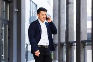 arg och allvarlig framgångsrik asiatisk affärsman förklarar information till anställda använder sig av telefon foto