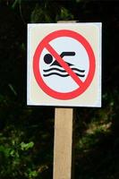 en pelare med en tecken betecknar en förbjuda på simning. de tecken visar en överstruken flytande person foto