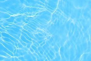 defokusering suddig transparent blå färgad klar lugna vatten yta textur med stänk, bubbla. lysande blå vatten krusning bakgrund. yta av vatten i simning slå samman. blå bubbla vatten lysande. foto