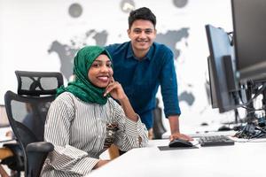 multietnisk börja företag team kvinna bär en hijab på möte i modern öppen planen kontor interiör brainstorming, arbetssätt på bärbar dator och skrivbordet dator. selektiv fokus foto