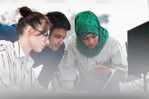 multietnisk börja företag team arab kvinna bär en hijab på möte i modern öppen planen kontor interiör brainstorming, arbetssätt på bärbar dator och skrivbordet dator. selektiv fokus foto