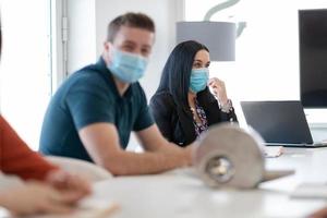 verklig företag människor på möte bär skyddande mask foto