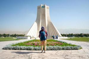 teheran, Iran, 2022 -backpacker kvinna promenad förbi azadi torn - känd landmärke i tehran i huvudstad av iran. kvinna rättigheter och och turism i mitten öst foto