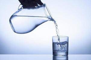vatten som hälls från en kanna i ett glas foto