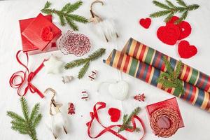 jul bakgrund med gåva lådor, band, snöre, papper rullar, stickat hjärtan och jul prydnad. foto
