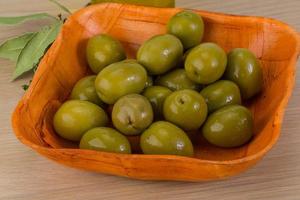 grön oliver i en skål på trä- bakgrund foto